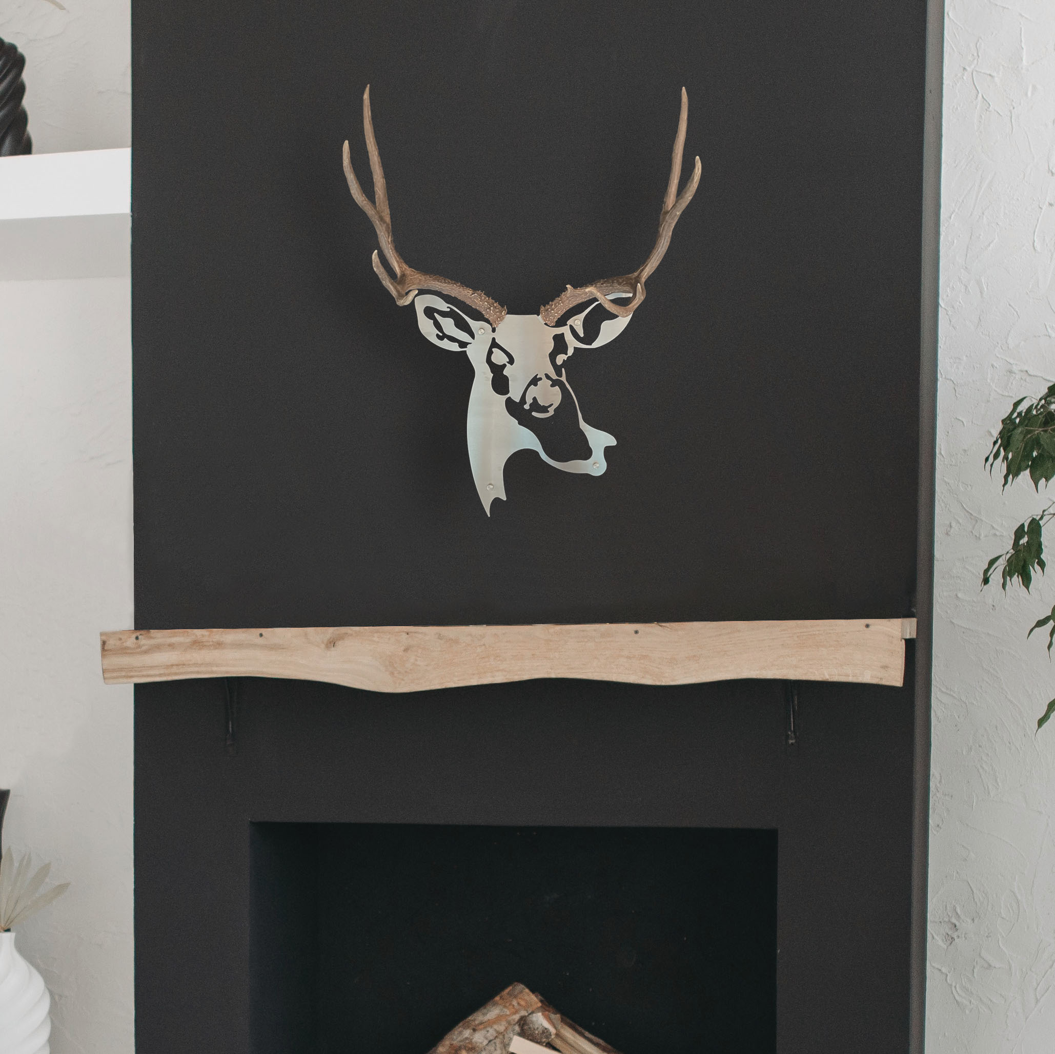 A metal wall decor made from real shed Deer antlers mounted on a metal head above a fireplace